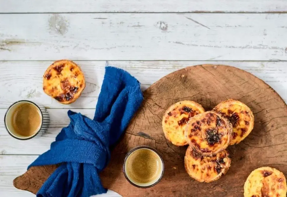 Pastéis de nata warm serveren met kaneel en poedersuiker
